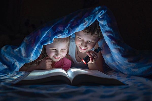 bambini sotto la coperta leggono