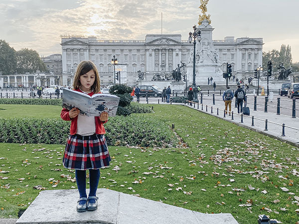 Bambina legge mary Poppins, sullo sfondo buckingham palace