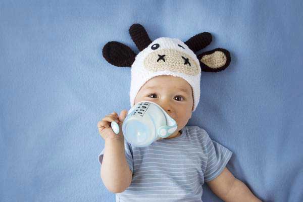 bambino con capppello a mucca beve latte