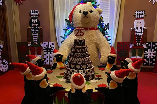 pinguini pupazzi e orso pupazzo seduti a tavolata di Natale
