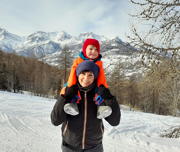 mamma con bambino sulle spalle nella neve