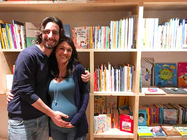 marito abbraccia moglie incinta in una libreria