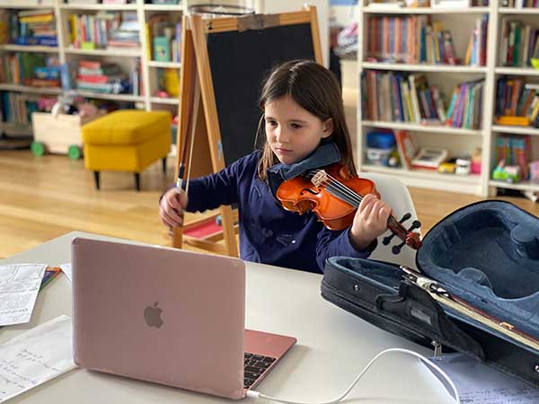 bambina suona violino davanti al computer