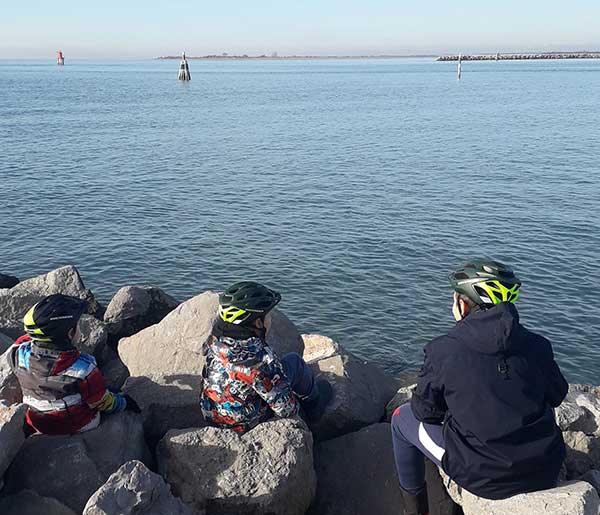 bambini di spalle co ncasco bici guardano il mare