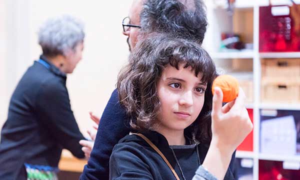 bambina al museo guarda una palla arancione