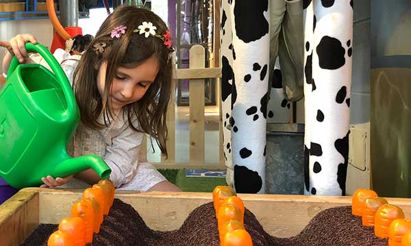 bambina gioca in museo per bambini innaffia orto