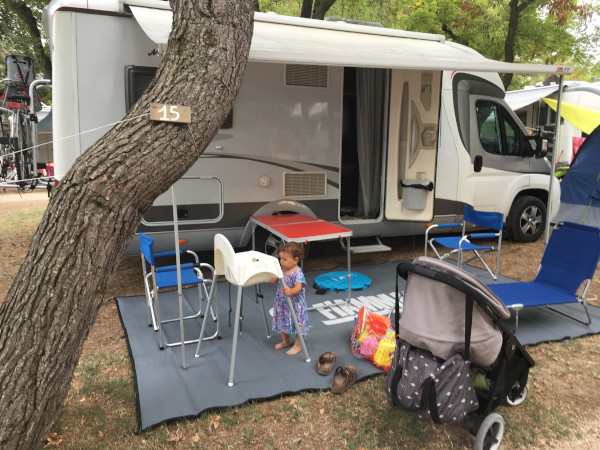 piazzola con camper allestito per l'esterno con tavolo e sedie