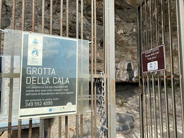 cancello della grotta della cala con numero di telefono per prenotare la visita