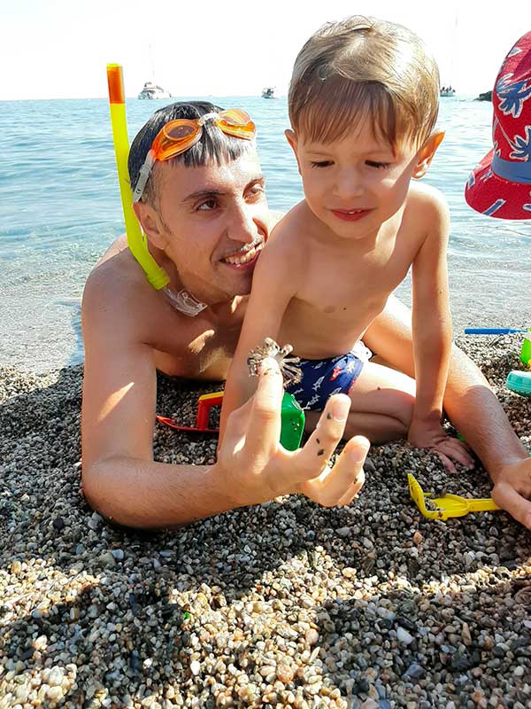 papà mostra granchio a bambin osulla spiaggia