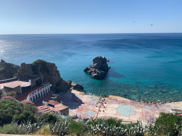 spiaggia vista dall'alto con mare blu e scogli