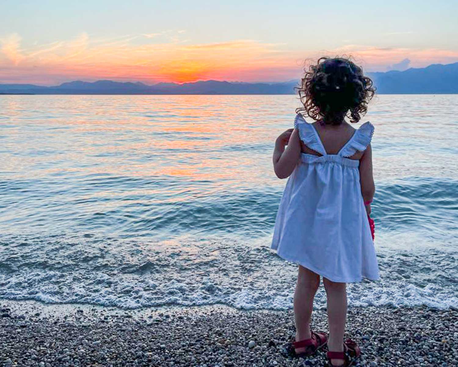 bambina di spalle in riva al lago di Garda