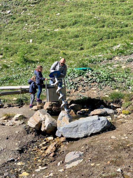 papà con bambine che giocano con trivella d'acqua