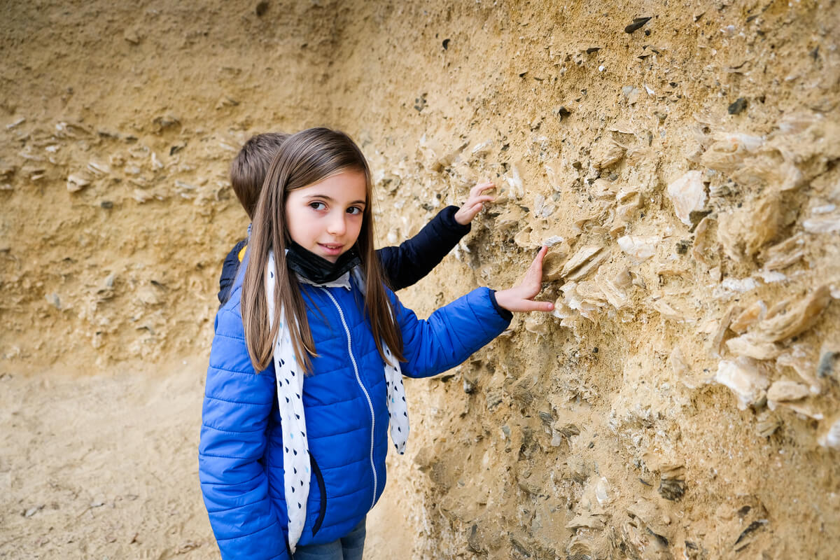 bambini toccano la parete del geosito con i fossili