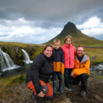 famiglia in Islanda davanti a una cascata con un monte sullo sfondo. Itinerario in Islanda low cost