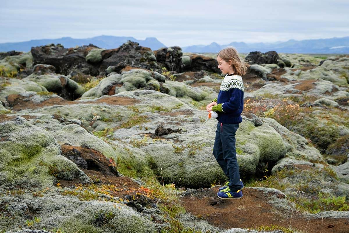 bambina con maglione islandese in un campo di lava in Islanda