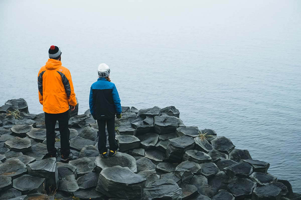 papà e figlia sulle scogliere di basalto di Hofsós davanti all'oceano nella nebbia