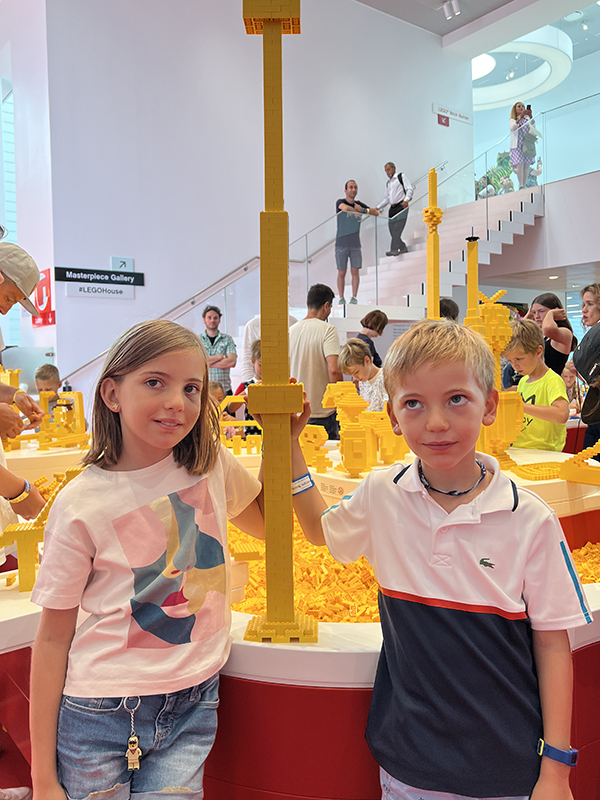 due bambini con una costruzione a torre gialla di lego