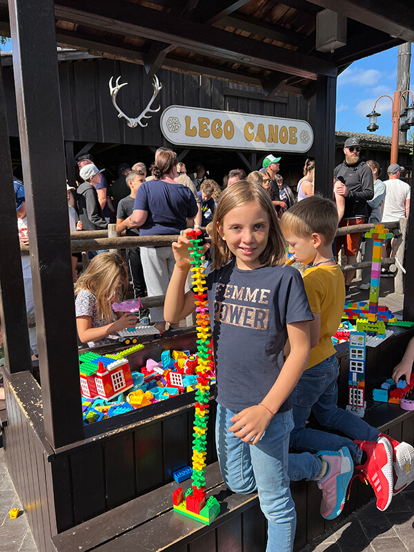 Bambini giocano con lego in una zona apposita lungo la coda dell'attrazione lego canoe