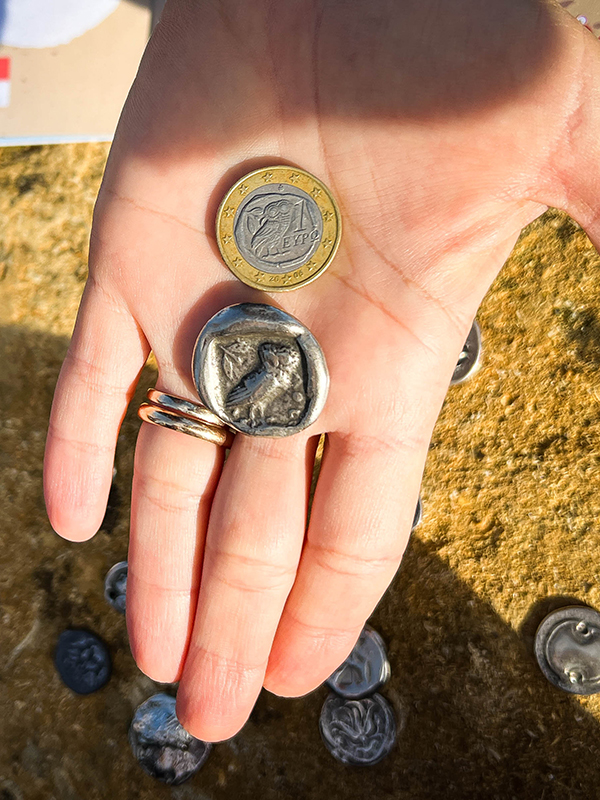 mano con due monete con l'immagine della civetta