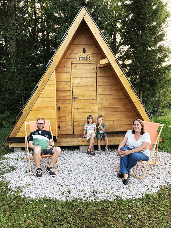 famiglia di quattro persone davanti alla casetta di legno nel glamping in Slovenia