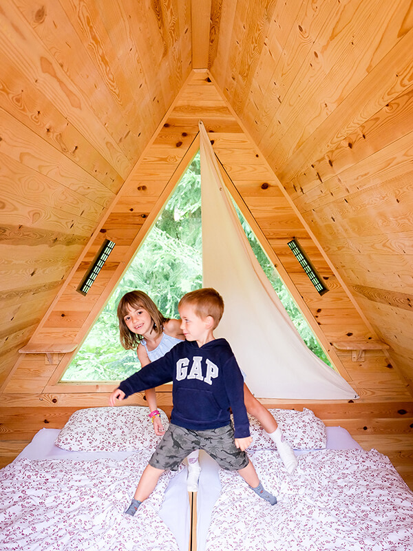 bambini dentro la casetta di legno sul letto al glamping in Slovenia