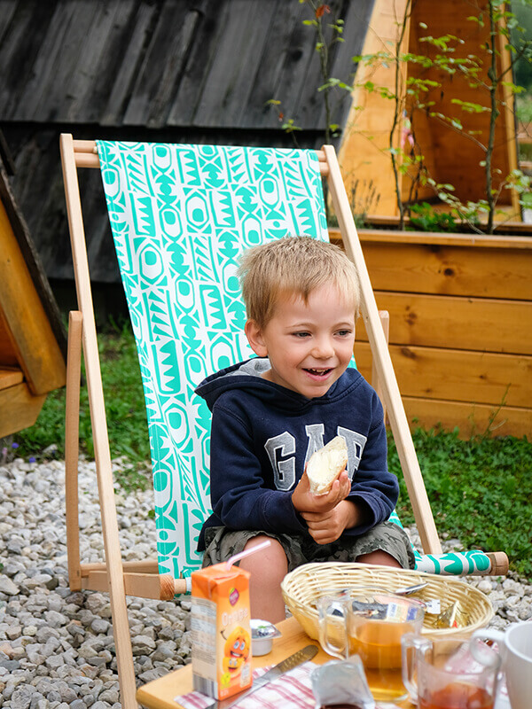 bambino fa colazione seduto sulla sdraio del campeggio