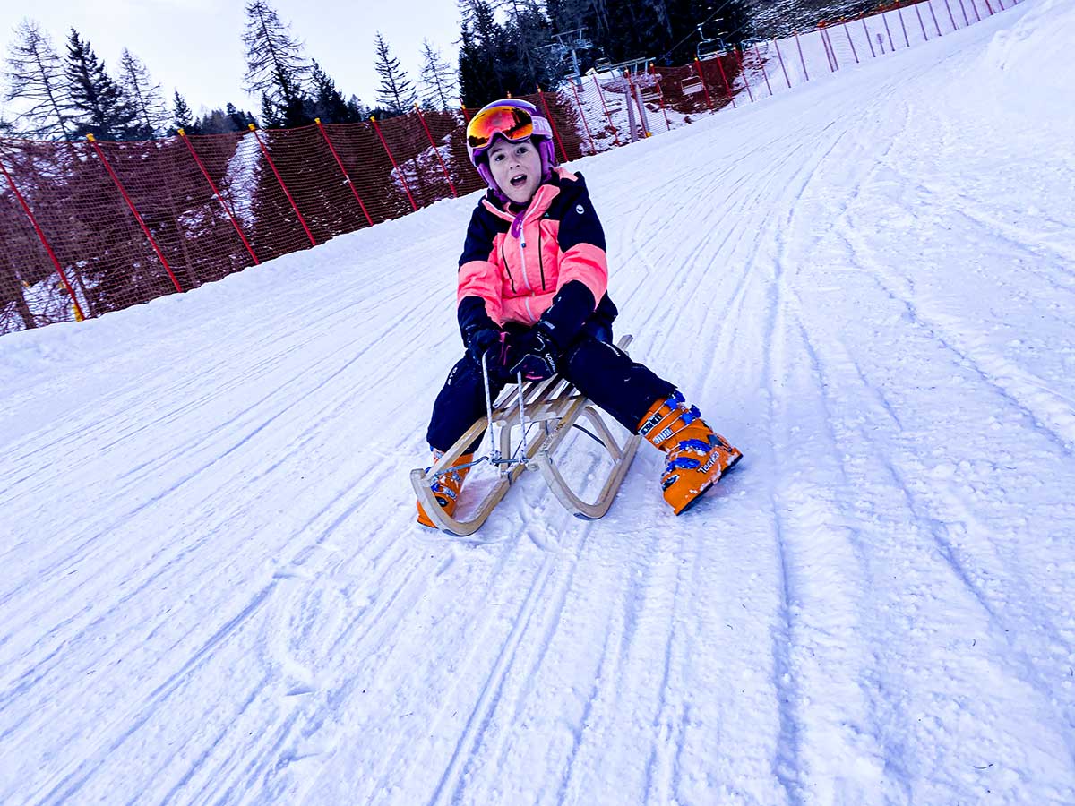 bambina su slittino sulla pista slitta a gardonè