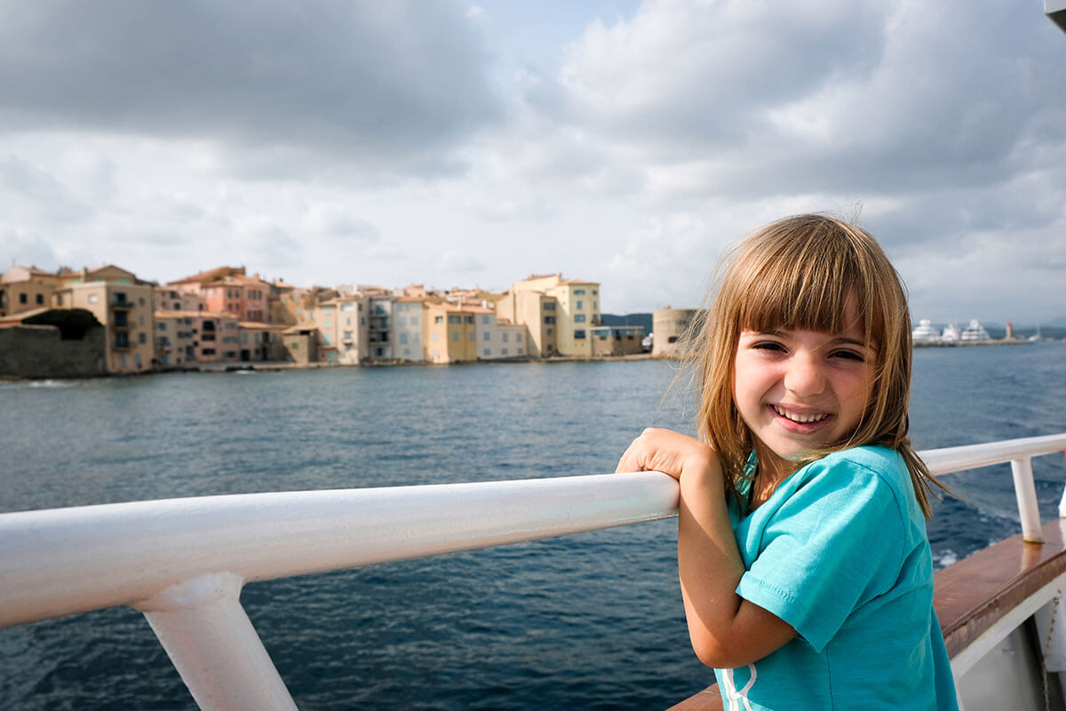 bambina sulla barca e saint Tropez sullo sfondo