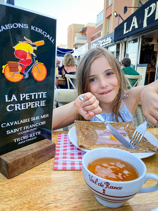 bambina mangia crepa e beve succo di mela