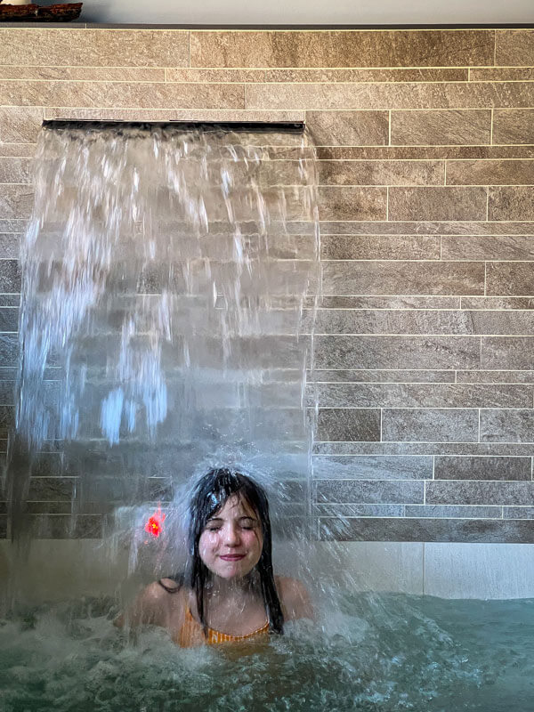 bambina sotto la cascata nella spa
