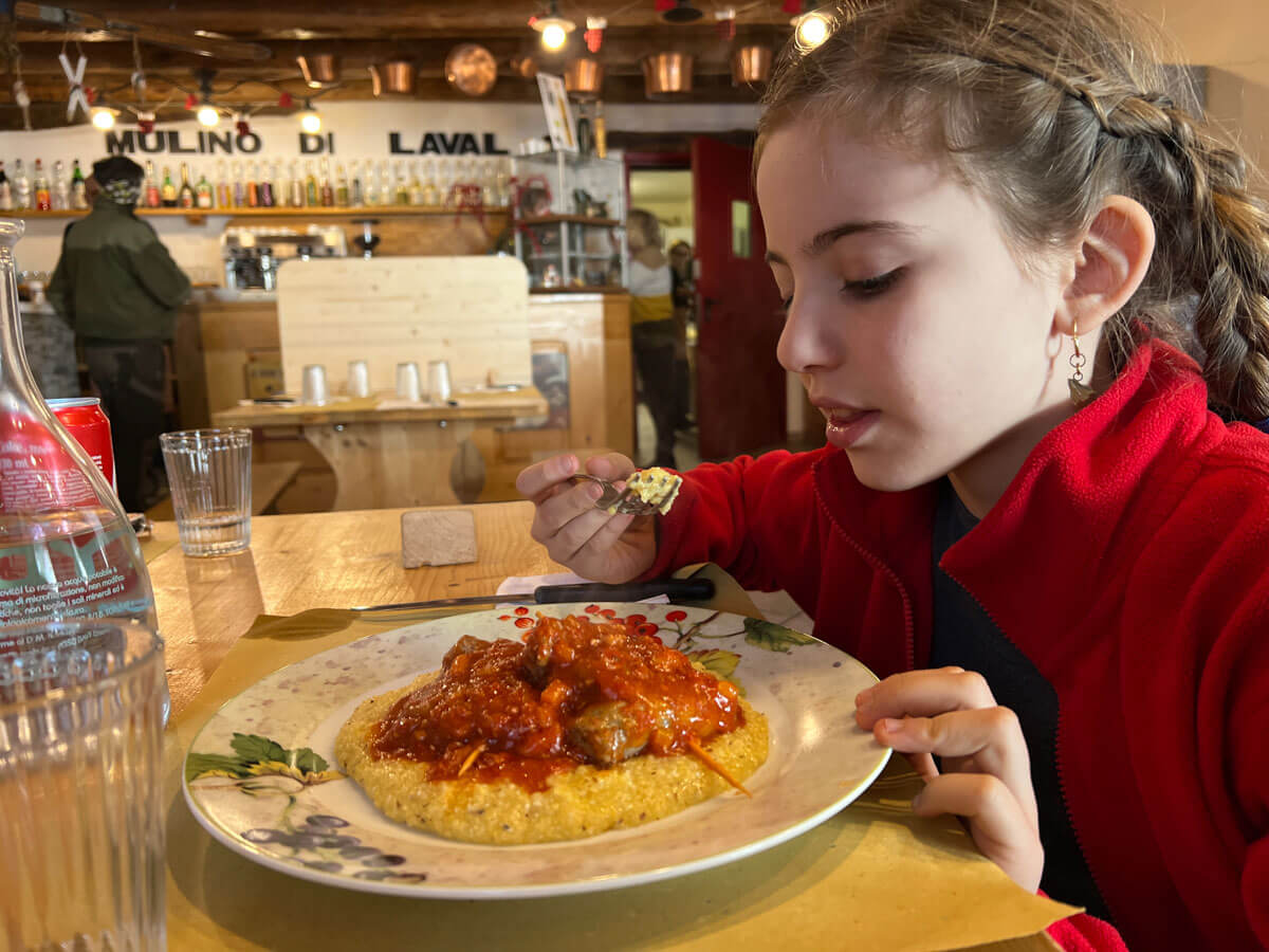 bambina che mangia polenta e salsiccia