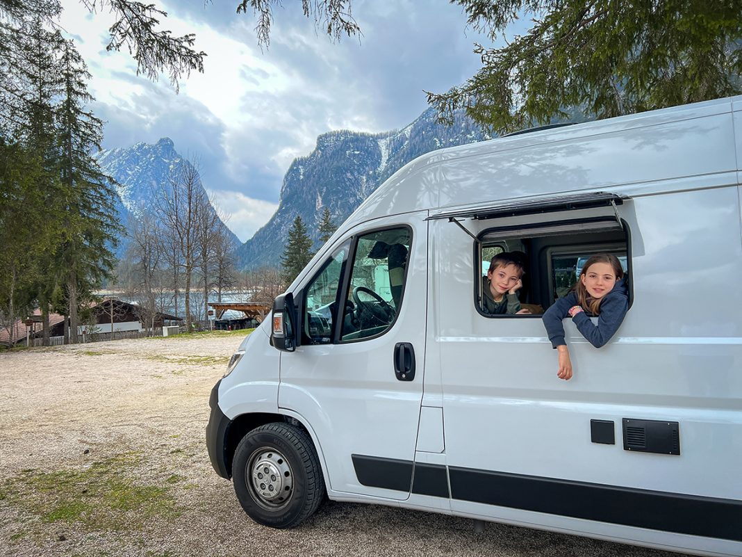 due bambini si affacciano dal finestrino del van sul lago di Dobbiaco