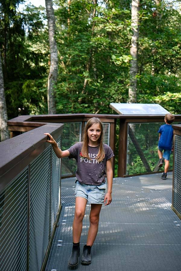 bambina sulla passerella tra gli alberi