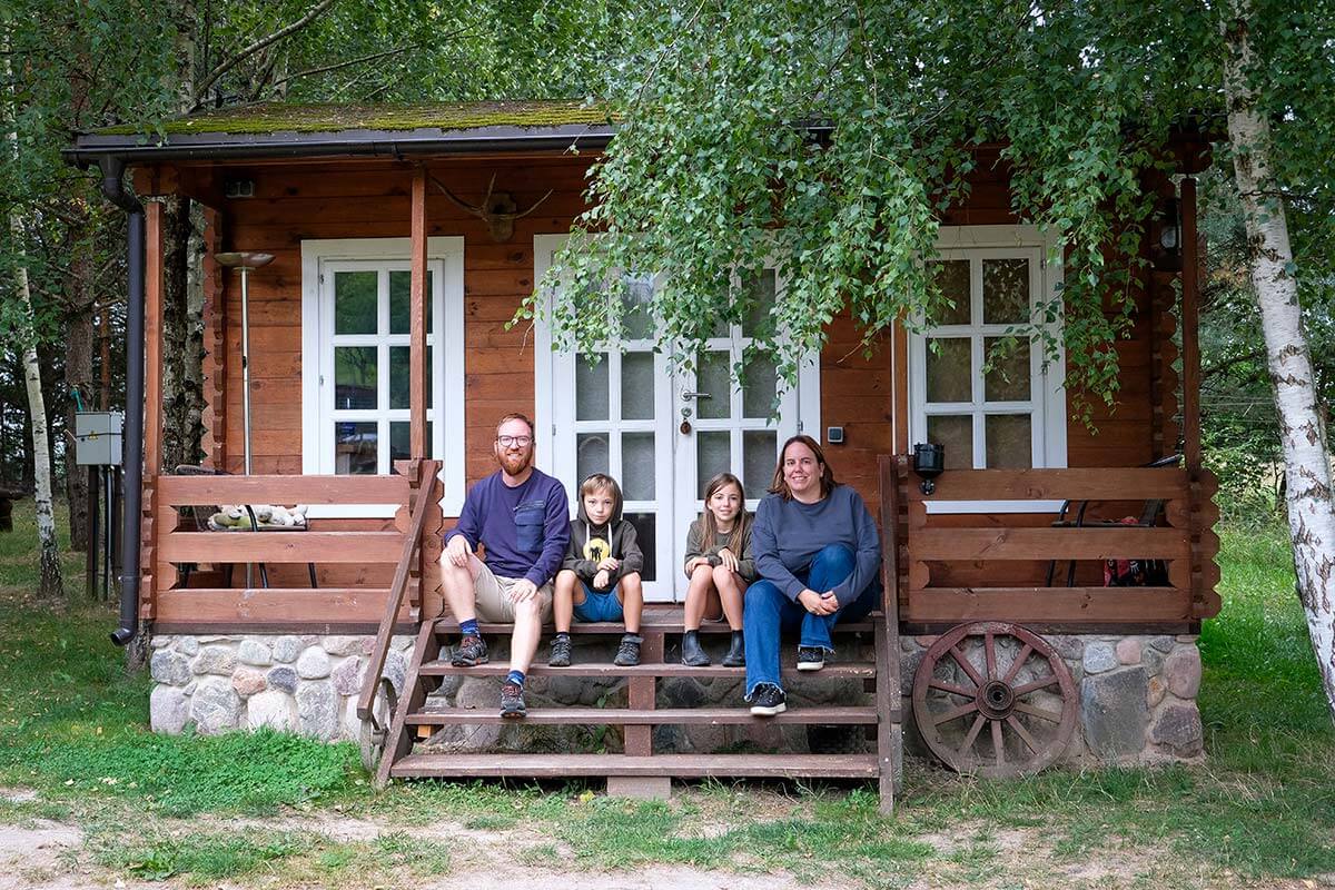 casetta in legno con finestre bianche e famiglia seduta sui gradini del patio