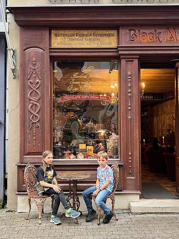 due bambini seduti nei tavolini esterni del bar Black Magic a Riga