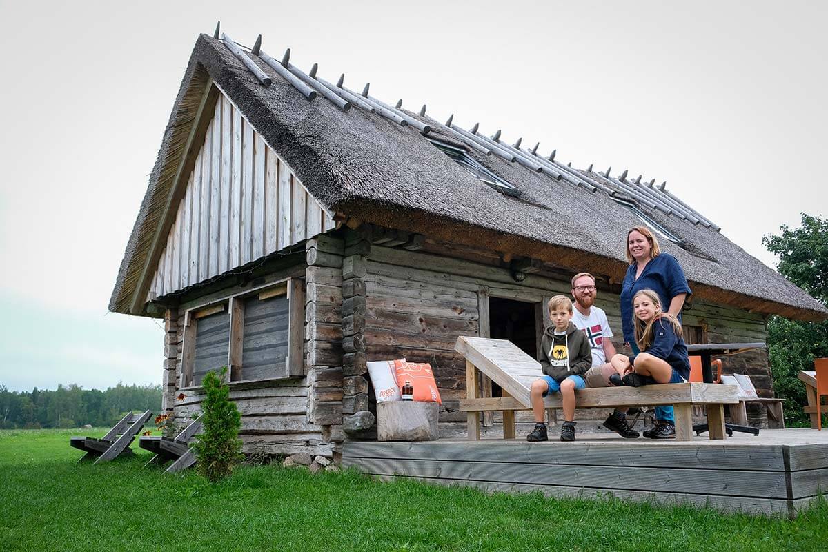Famiglia davanti alla casa in legno con tetto in paglia