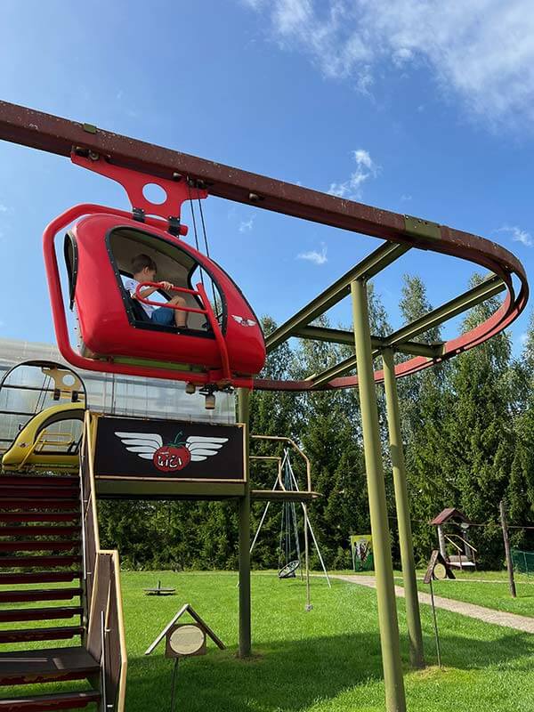 Parco giochi con vecchi giochi, due bambini su una teleferica rossa