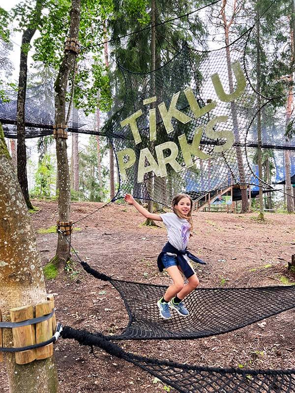 bambina salta su una rete sotto al Parco tra gli alberi