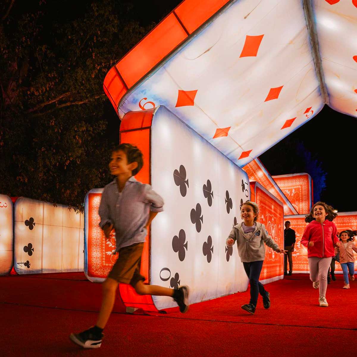 bambini corrono tra le carte luminose e giganti di Alice in The wonderland