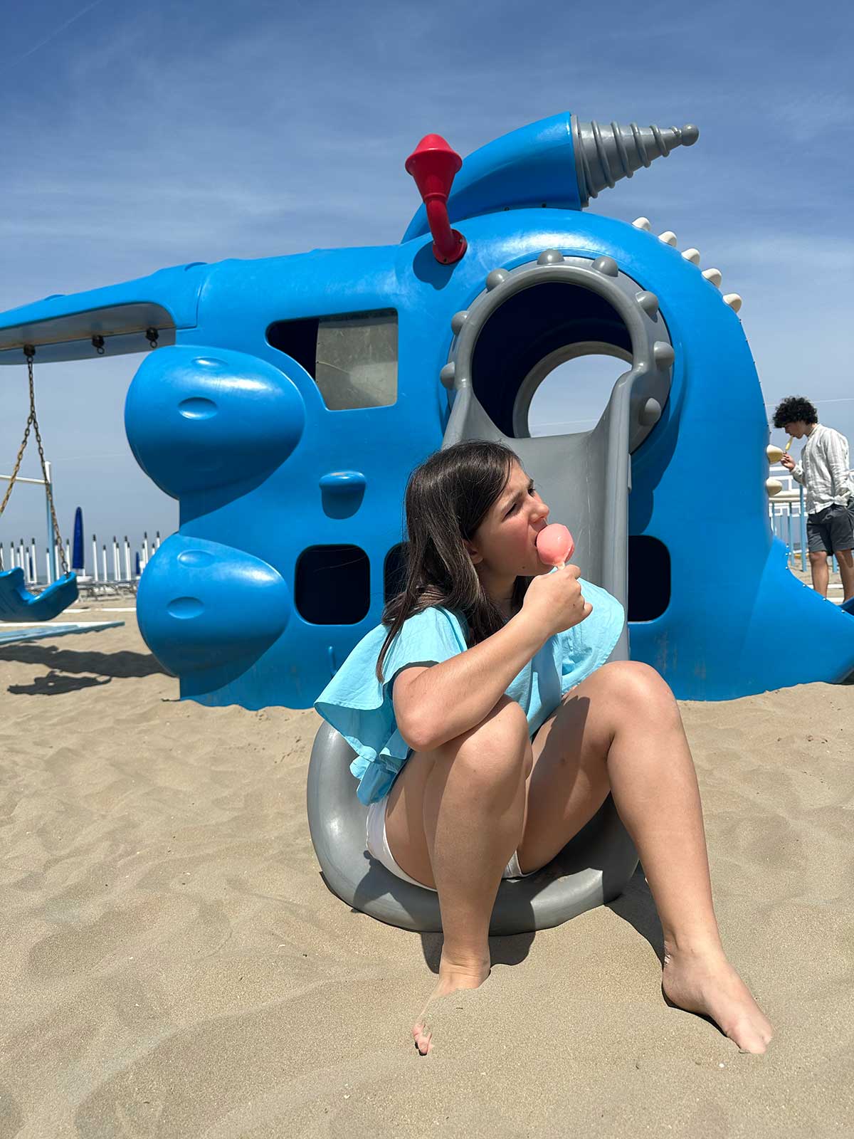 bambina mangia ghiacciolo sulla sabbia