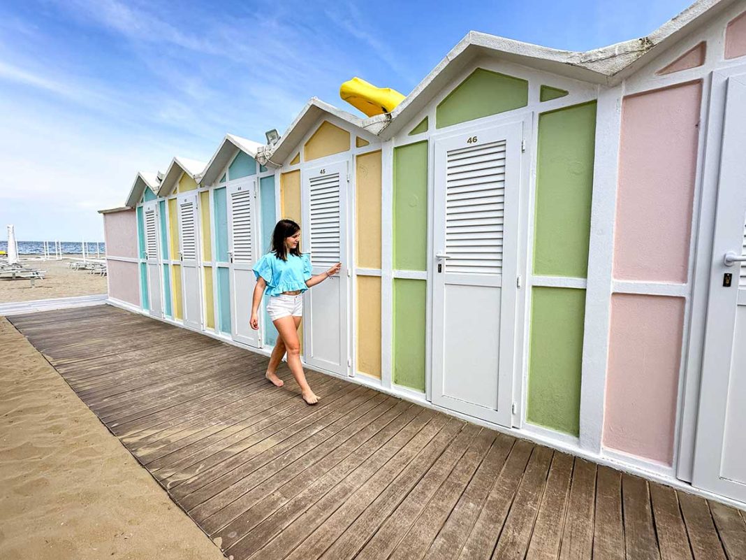 Bambina cammina davanti alle cabine colorate sulla spiaggia a Riccione