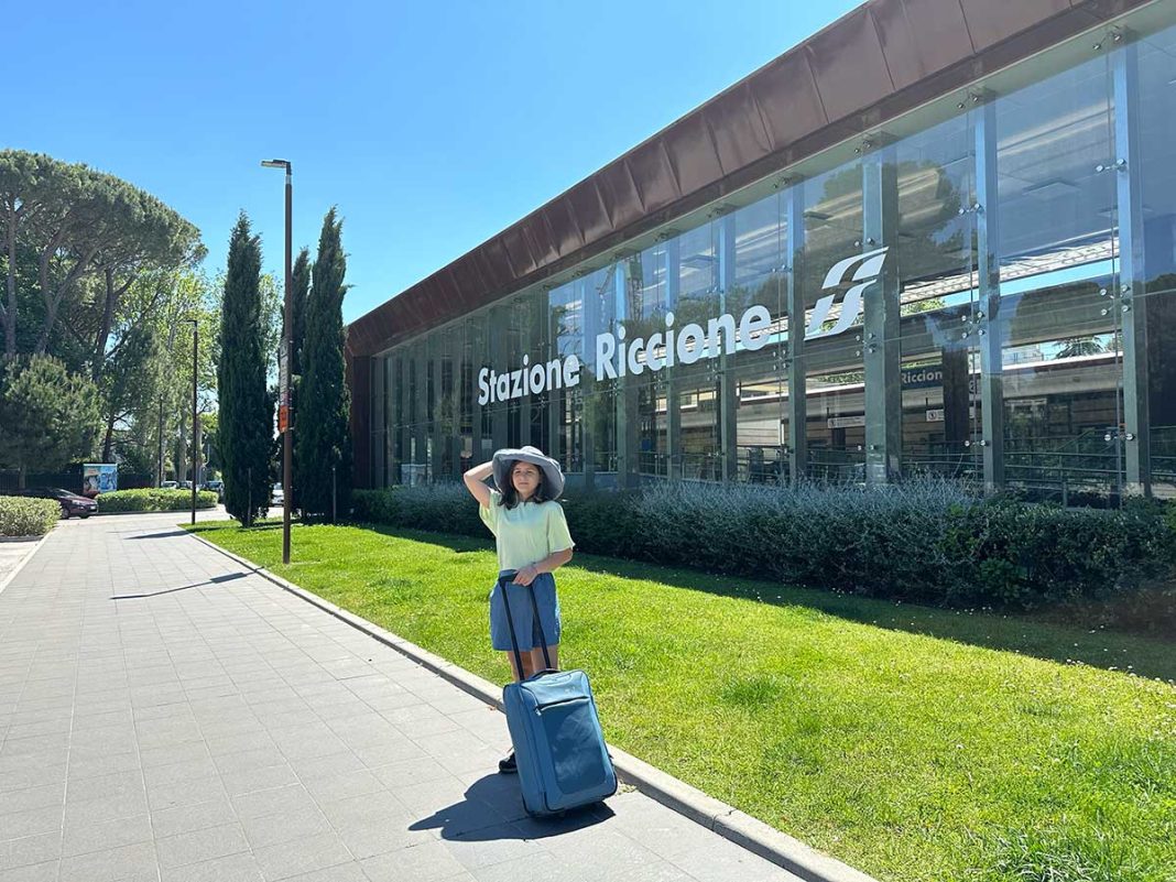 bambina con valigia davanti alla stazione di Riccione