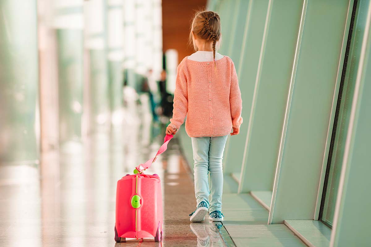 Bambina trascina una valigia cavalcabile su 4 ruote