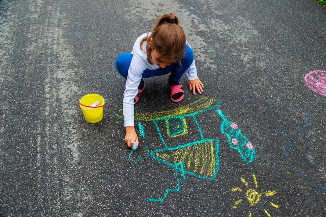 bambina disegna con gessetti per strada