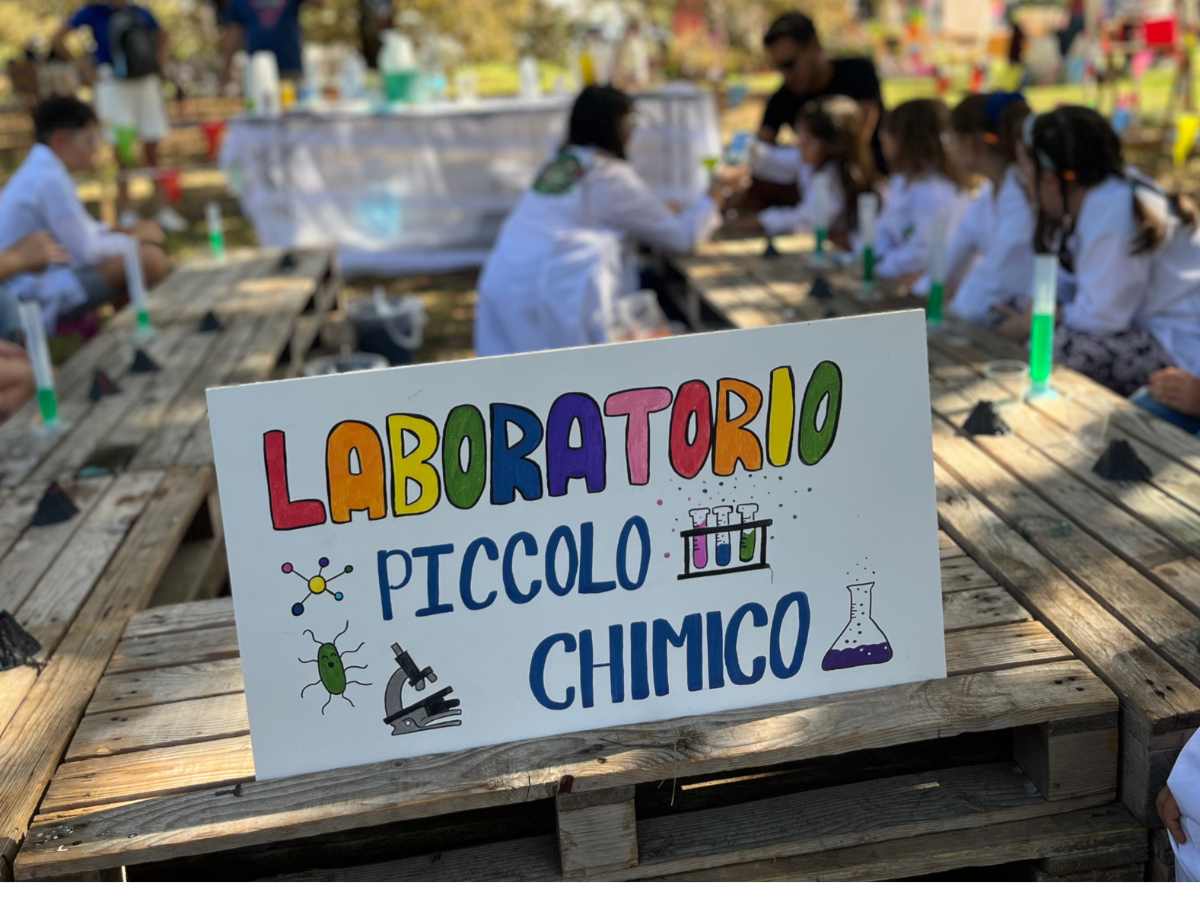 cartello laboratorio piccolo chimico con bambini sullo sfondo vestiti da chimici