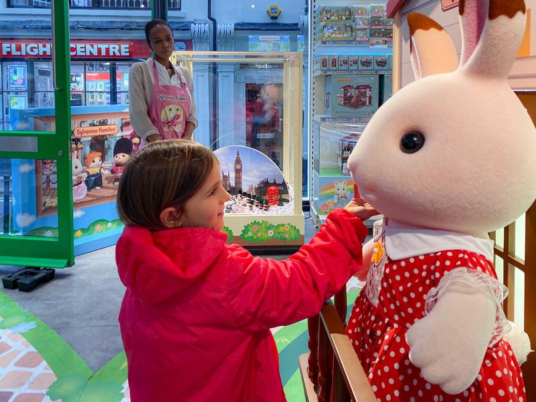 bambina con silvenian family in negozio di giocattoli a Londra