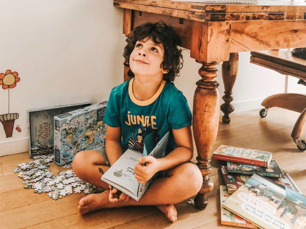 bambino intorno a tanti libri per imparare a scoprire il mondo