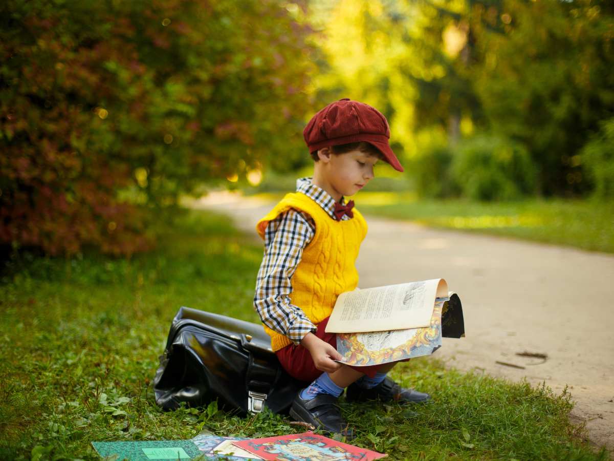 bambino che legge un libro all'aperto per scoprire il mondo prima di partire